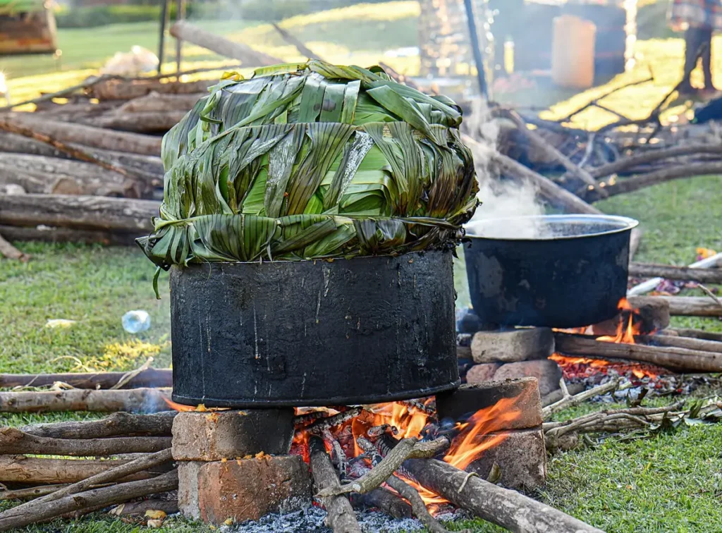 Matooke steaming in banana leaves over a wood fire