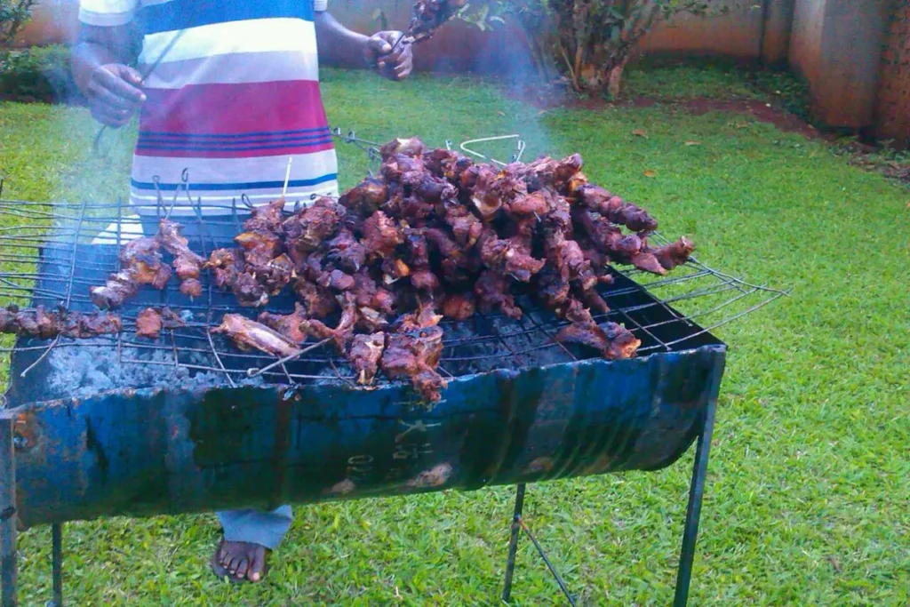 Skewers of meat roasting on a charcoal grill in Uganda