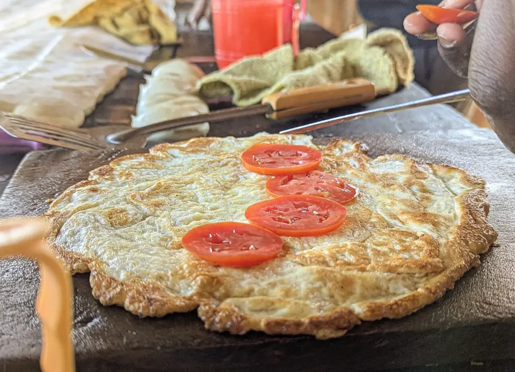 Fried egg with tomato slices ready to be rolled into a chapati