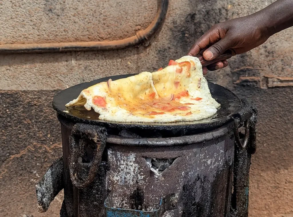 Street vendor flipping an egg omelette for a rolex in Uganda