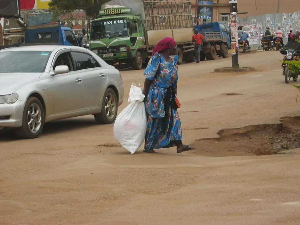 Woman in a blue gomesi walking along a street in Uganda