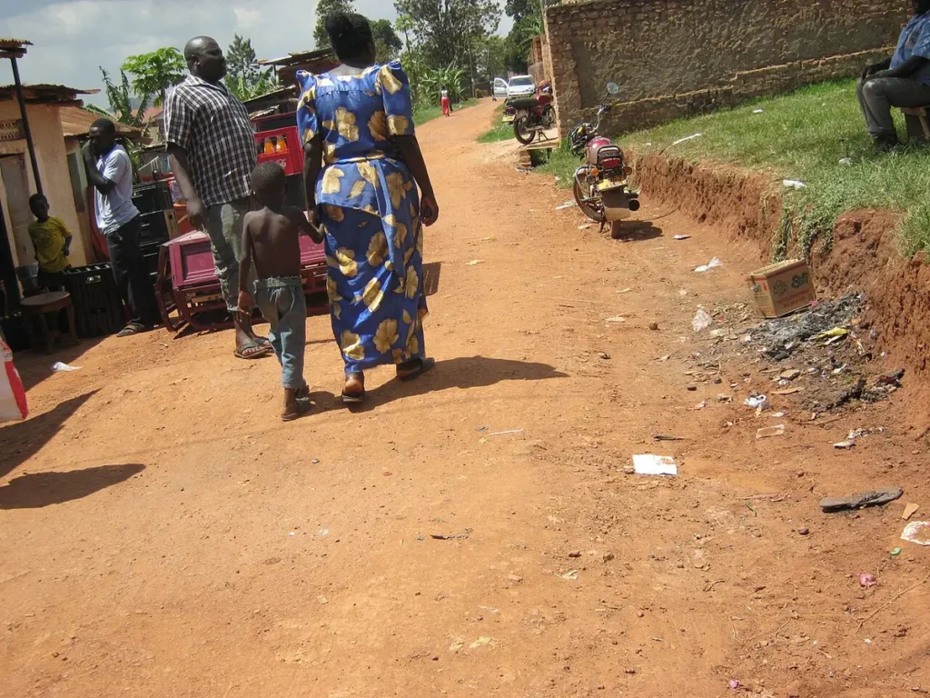 Woman in a gomesi walking with a child